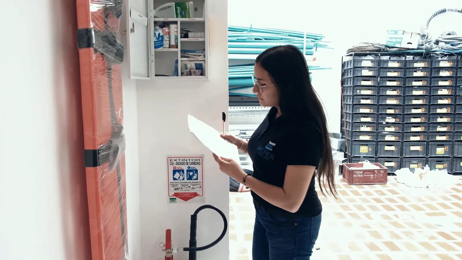 Consultora de MEPER revisando una estación de emergencia en la bodega de un cliente